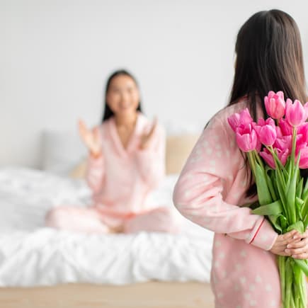 Mädchen versteckt Blumen für ihre Mutter hinter ihrem Rücken