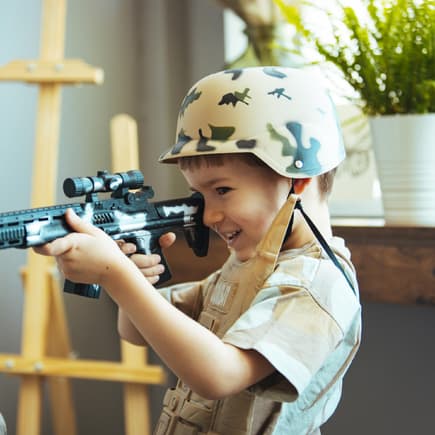 Kleiner Junge mit Tarn-Helm und Spielzeugwaffe