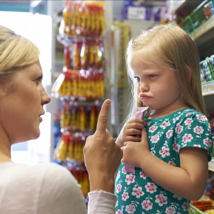 Mama schimpft mit ihrer Tochter, die im Supermarkt einen Riegel geholt hat 