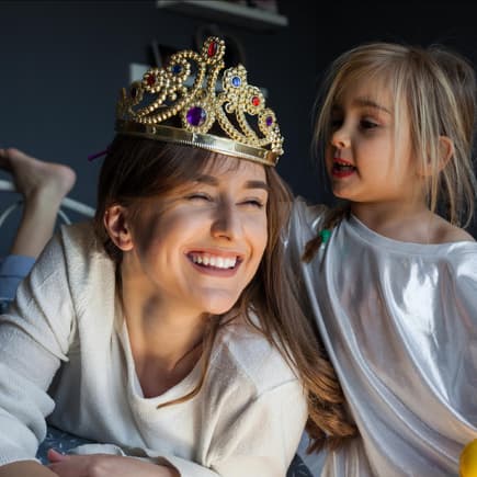 Kleines Mädchen setzt der Mutter eine Krone auf