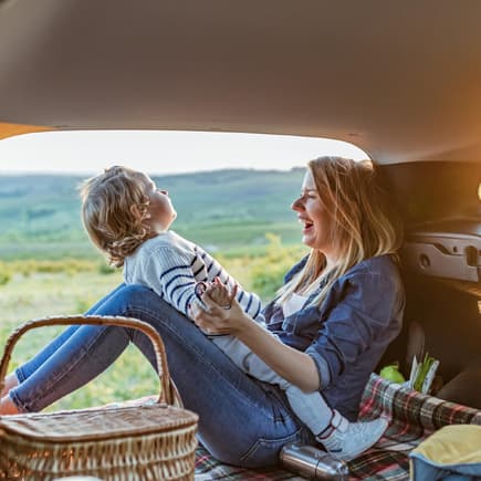 Mutter und Kind sitzen im Van und haben ein Picknick dabei.