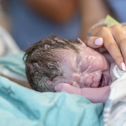 Ein neugeborenes Baby liegt auf dem Bauch seiner Mutter.