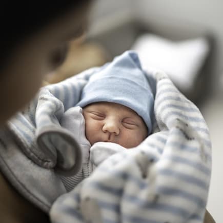 Ein kleines Baby liegt in den Armen seiner Mutter.