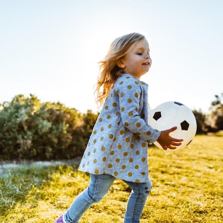 Ein Mädchen spielt mit einem Ball.