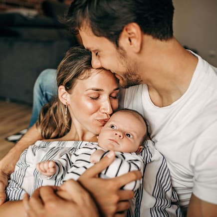 Mutter und Vater halten ihr Baby im Arm.