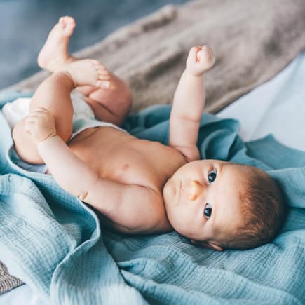 Ein Baby liegt auf einem blauen Tuch.