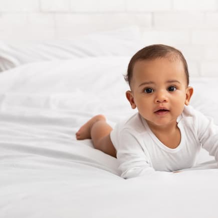 Ein Baby krabbelt auf dem Bett.