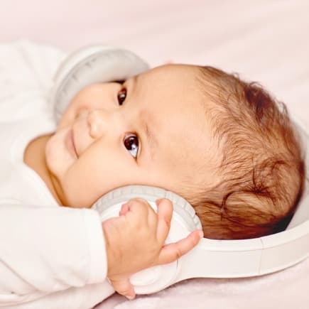 Ein Baby hat Kopfhörer auf den Ohren. 