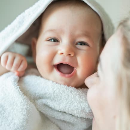 Ein Baby ist in ein Handtuch eingewickelt und lacht.