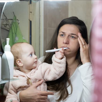 Eine müde Mama und ihr Baby im Badezimmer. 