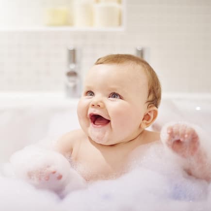 Baby sitzt in der Badewanne mit viel Schaum