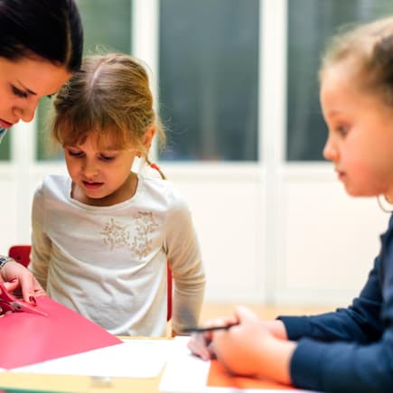 Erzieherin bastelt mit Kindern.