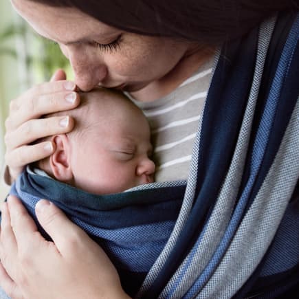 Mama hat Neugeborenes in Babytrage
