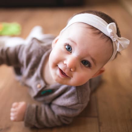 Ein Baby krabbelt neben Spielsachen auf dem Boden.