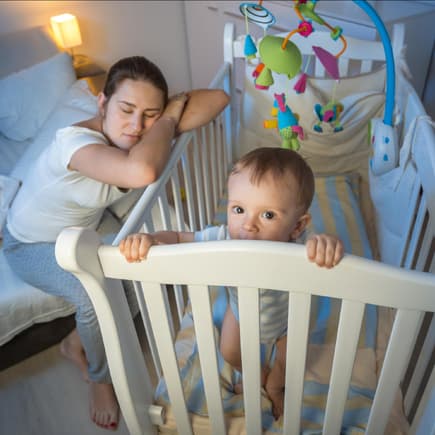 Baby steht nachts wach im Bett.