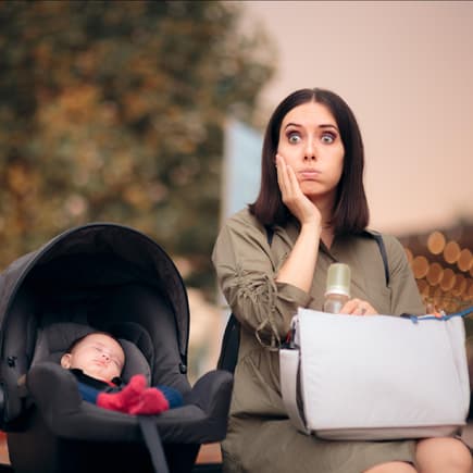 Vergessliche Mama sitzt neben Baby in Babyschale.