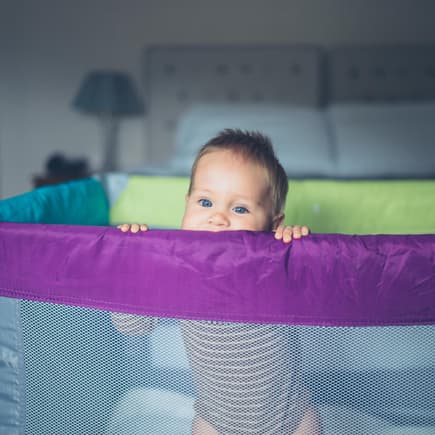 Baby schaut aus Reisebett