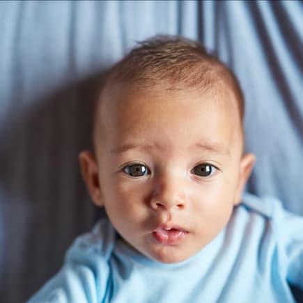 Ein kleines Baby, das süß in die Kamera guckt. 