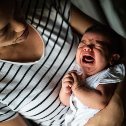 Mutter hält ihr schreiendes Baby im Arm.