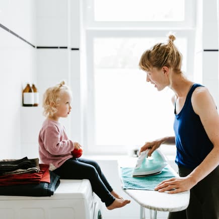 Mutter bügelt und spricht mit Tochter.