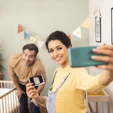 Junges Pärchen macht mit Ultraschallbild ein Selfie.