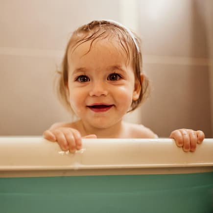 Baby-Mädchen schaut niedlich aus der Babywanne – aber wie lange?
