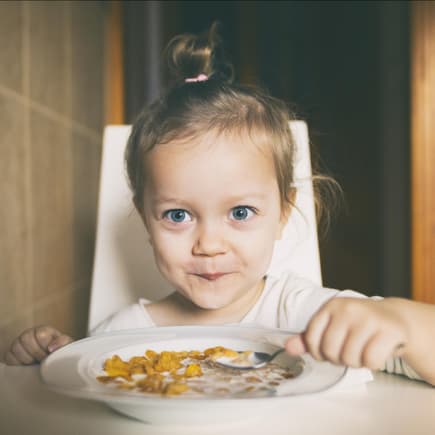 Mädchen freut sich über einen Teller Cornflakes