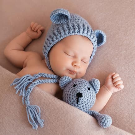 Kleiner Junge schläft mit seinem Teddy im Bett