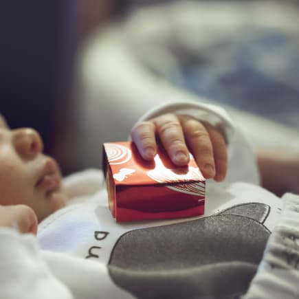 Baby hält Geschenk zur Geburt in der Hand