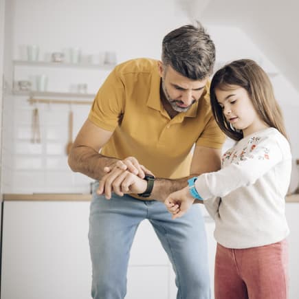 Papa und Tochter checken ihre Smartwatches
