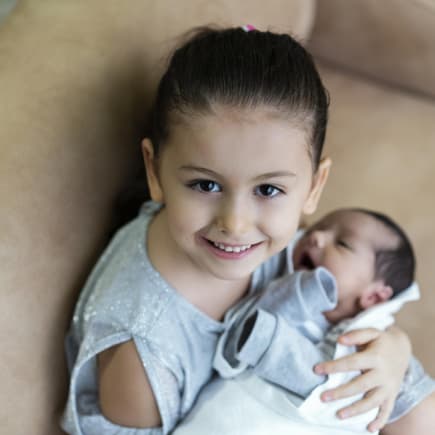 Mädchen hält Baby im Arm.