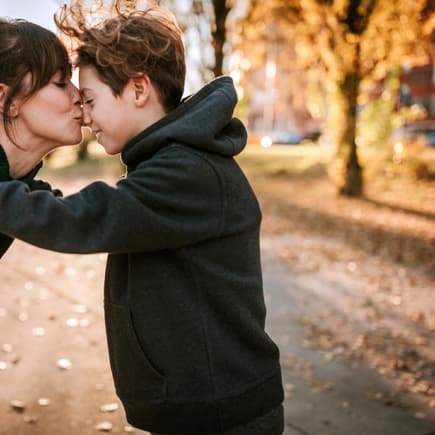 Eine Mutter küsst ihren Teenager-Jungen zärtlich auf die Nase. 