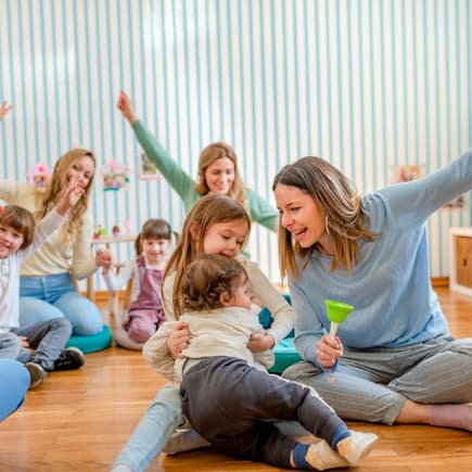 Erzieherinnen spielen mit Kita-Kindern und haben gemeinsam Spaß.