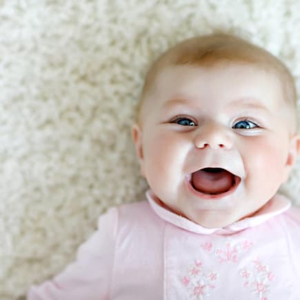 Baby-Mädchen mit biblischem Namen lacht fröhlich in die Kamera. 