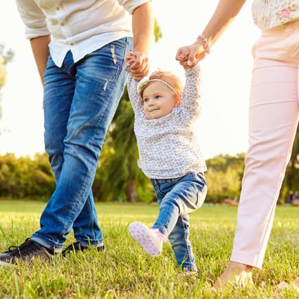 Baby übt das Laufen mit seinen Eltern
