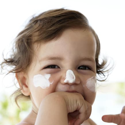 Kleines Kind mit Sonnencreme im Gesicht