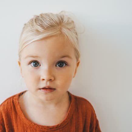 Blondes Mädchen schaut in die Kamera.