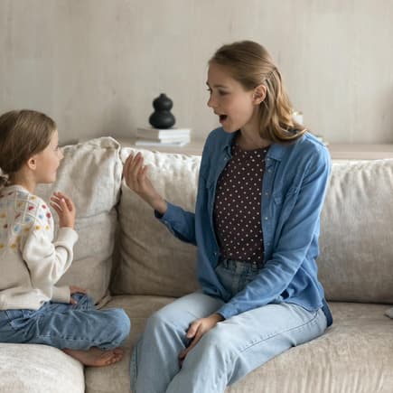 Mutter und Tochter unterhalten sich auf dem Sofa.