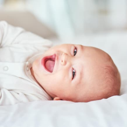 Ein kleiner Junge, der vor Freude strahlt und auf dem Bett liegt.