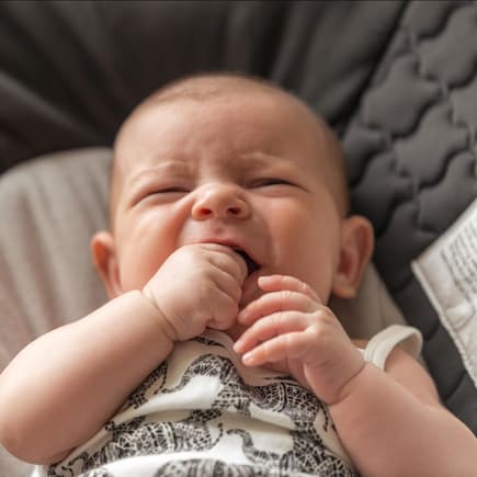 Quengeliges Baby kaut auf seiner Hand