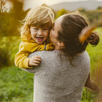Mama kuschelt draußen fröhlich mit ihrem Kleinkind