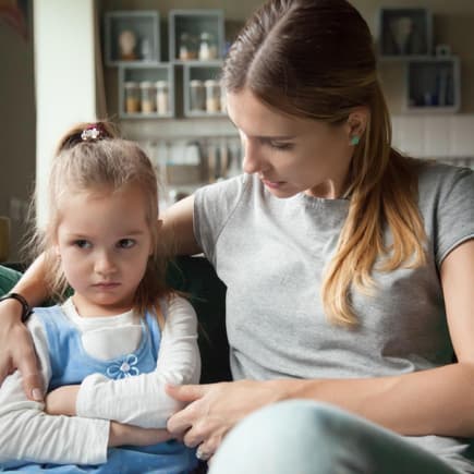 Junge Mutter spricht einfühlsam und liebevoll mit ihrer kleinen Tochter. 