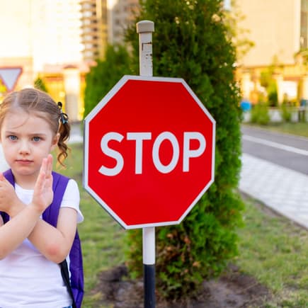 Grenzen ziehen: Kleines Schulmädchen sagt Nein an einem Stopp-Schild