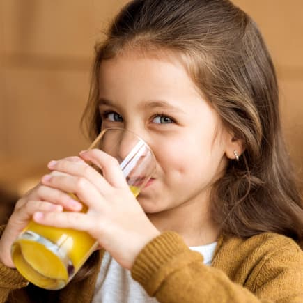 Lächelndes Mädchen trinkt ein Glas Orangensaft