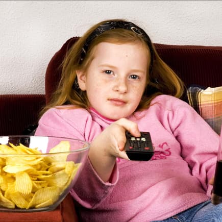 Mädchen mit Cola, Fernbedienung und Chips.