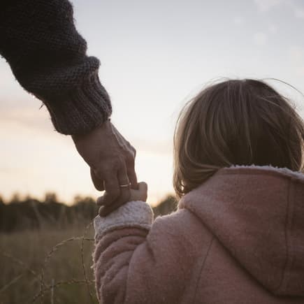 Vater hält die Hand seiner Tochter.