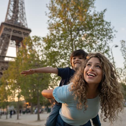 Eine Mutter und ihr Sohn spielen vor dem Eiffelturm in Paris, Frankreich. 