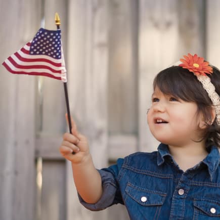Kleines Mädchen hält eine Amerika-Flagge in der Hand. 