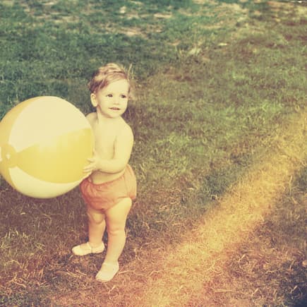 Kleinkind mit Wasserball im Garten