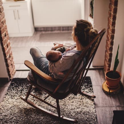 Mama stillt ihr Baby im Schaukelstuhl